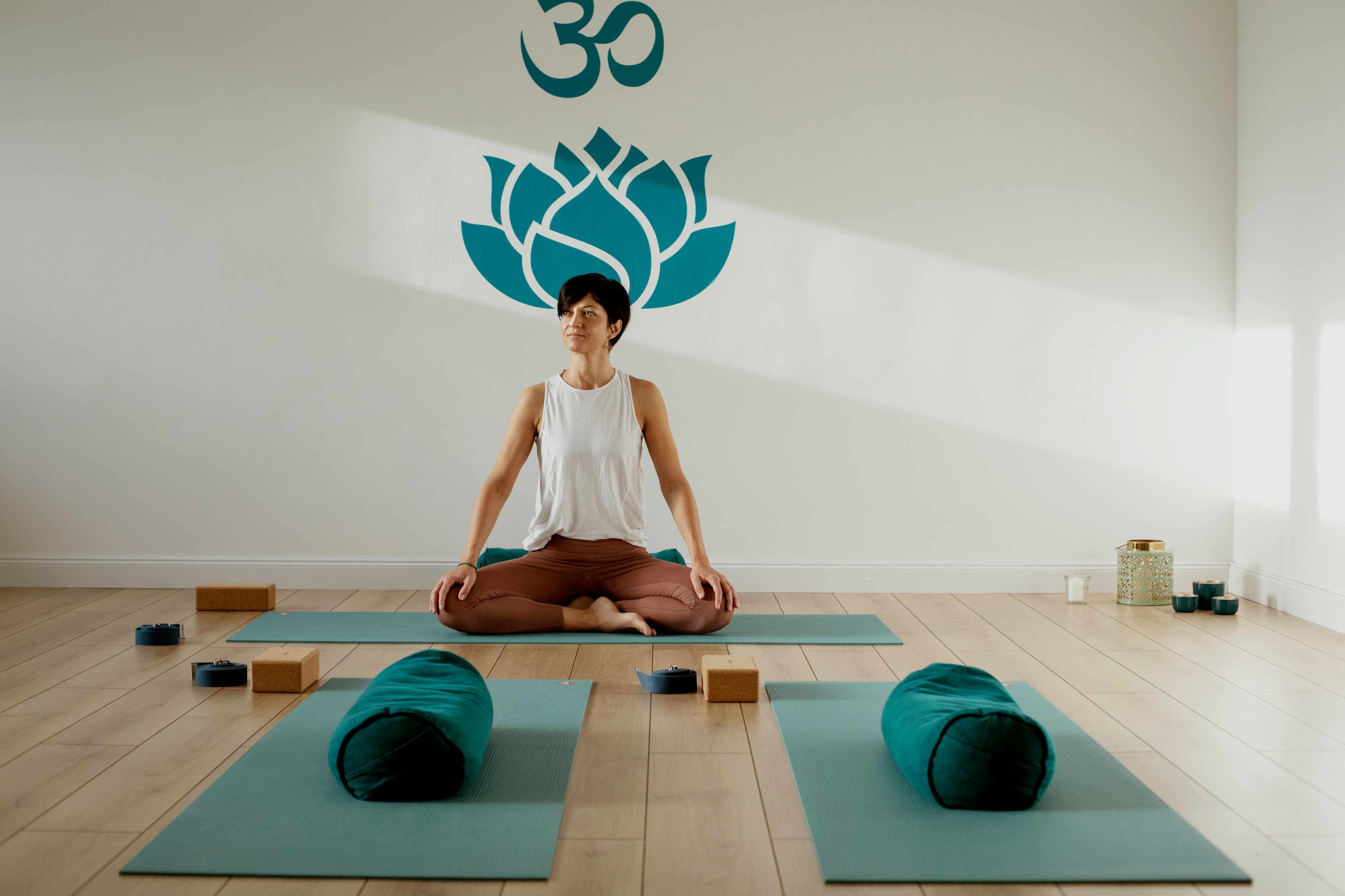 Frau praktiziert Yoga und Meditation in einem ruhigen Studio mit natürlichem Licht und entspannter Stimmung.