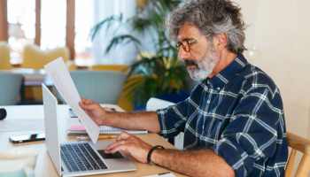 A man reading and using a laptop